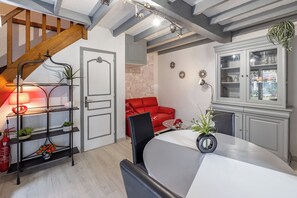 Un intérieur moderne avec un escalier, un coin repas, un canapé rouge et un meuble avec des portes en verre.