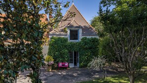A building with a triangular roof, a door, and a bench in front. - Gite La Tour - Cocoon for 2 with pool and nature (Saint-Geyrac)