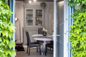 A dining area with a round table, two chairs, a cabinet with glass doors, and a potted plant. - Gite La Tour - Cocoon for 2 with pool and nature (Saint-Geyrac)