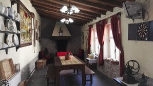 A rustic dining area with a stone fireplace, wooden beams, and a chandelier. - El Condado Casa Rural (Fuentes de Onoro)