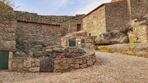 A stone building with a cobblestone courtyard, a wooden fence, and a stone wall. - El Condado Casa Rural (Fuentes de Onoro)