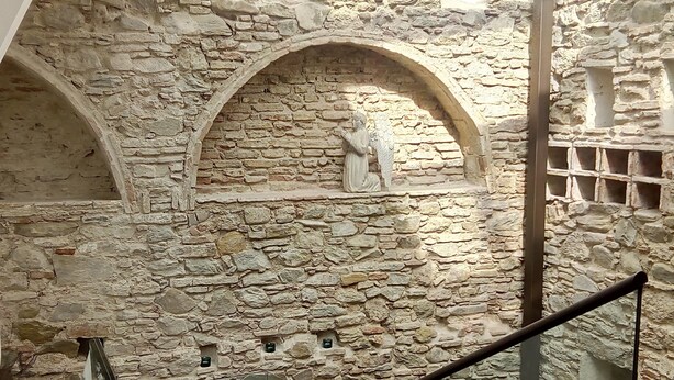 A stone-walled interior with a staircase and a statue of an angel. - Hospedería Diez y Seis (Tarifa)