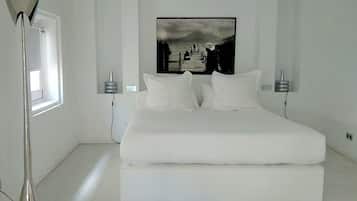 Un dormitorio moderno con una cama grande, una lámpara de pie y un cuadro enmarcado en la pared.