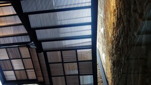 A modern interior with a stone wall and a metal partition with vertical slats. - Hospedería Diez y Seis (Tarifa)