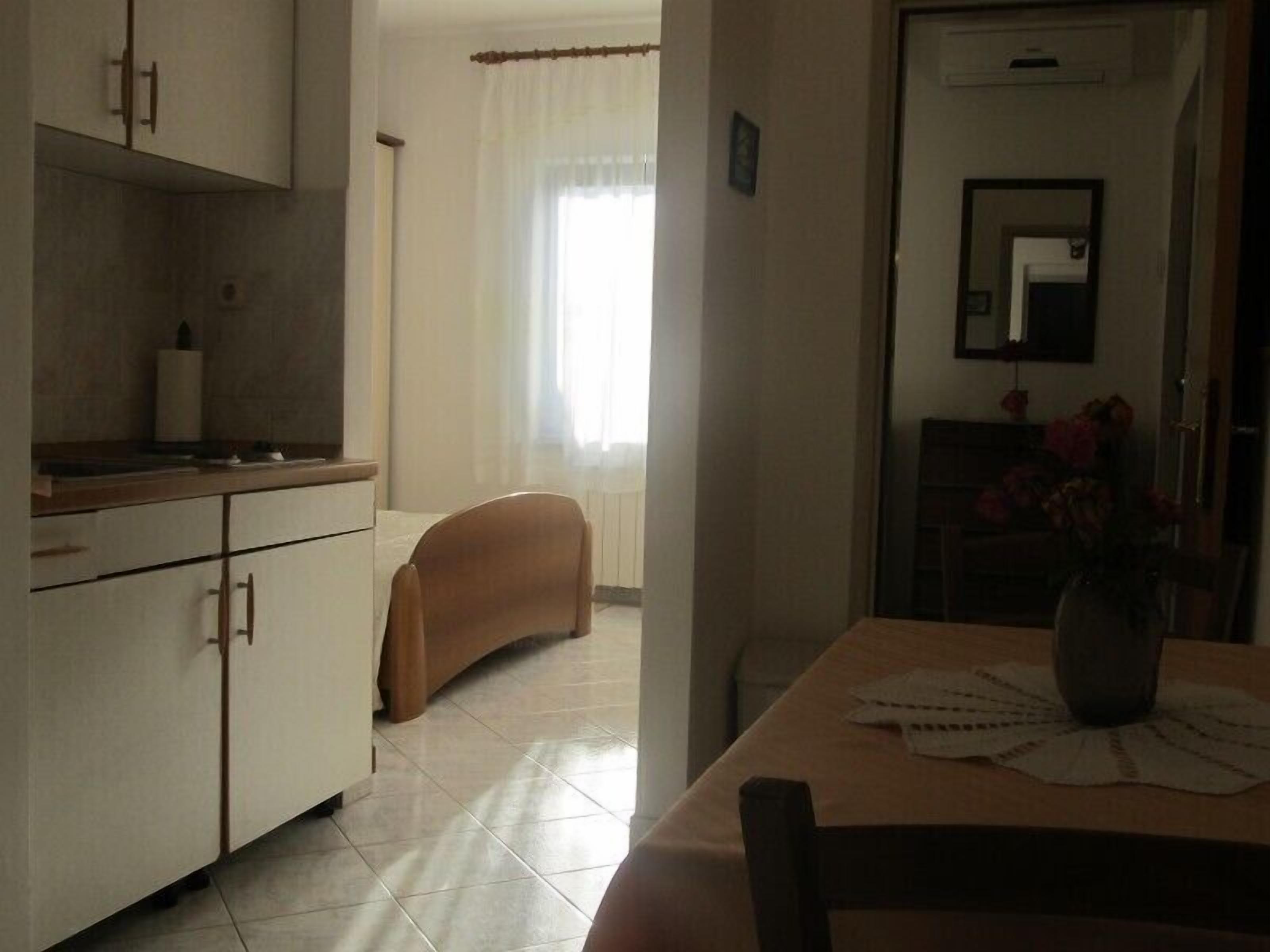 A kitchen with white cabinets, a wooden countertop, and a dining table with a vase of flowers.