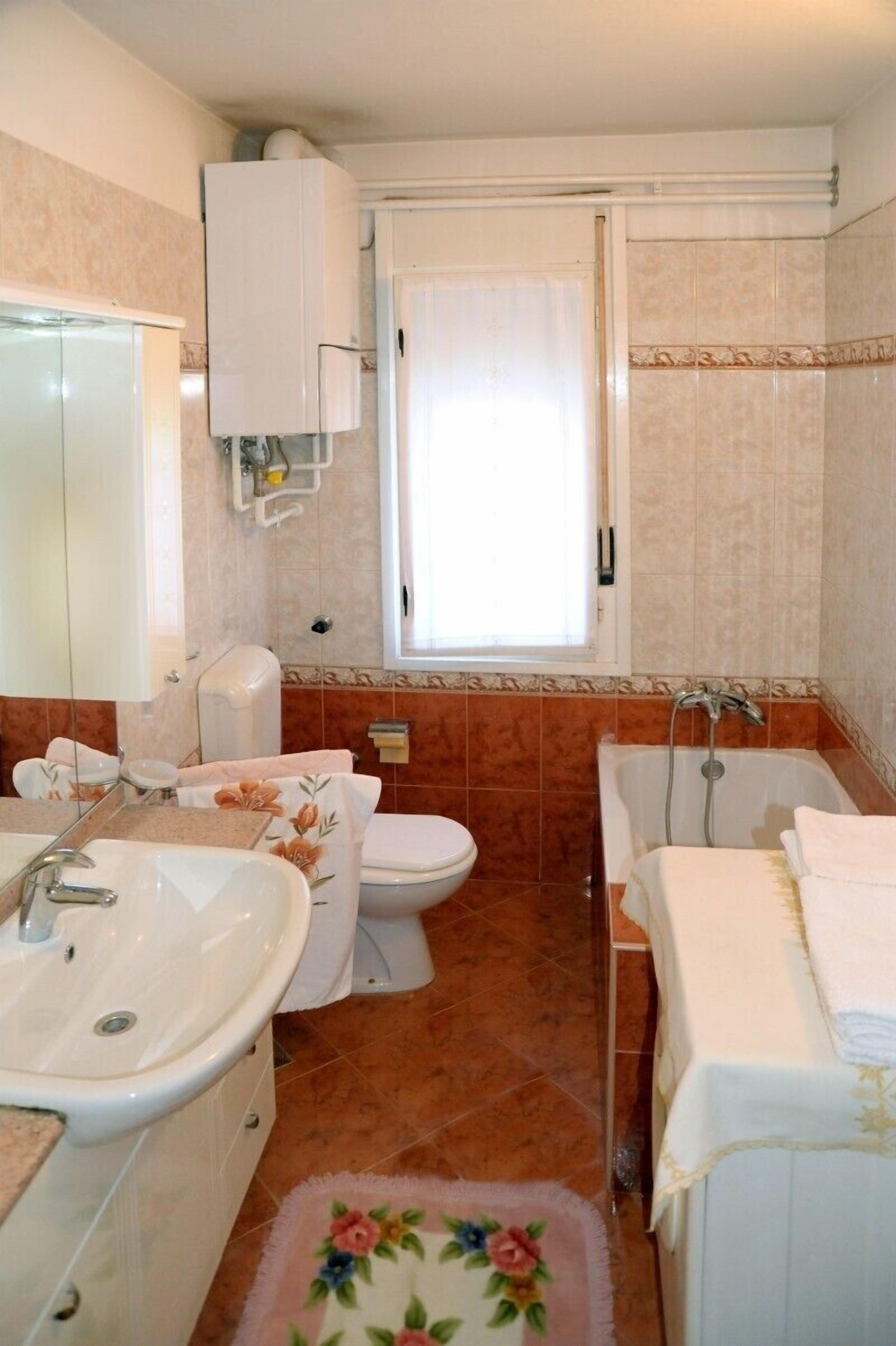 Une salle de bain équipée d’un lavabo, de toilettes, d’une baignoire et d’une fenêtre.