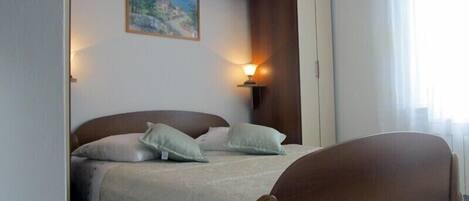 Une chambre à coucher avec un lit, des oreillers, une table de chevet, un tableau et une armoire.