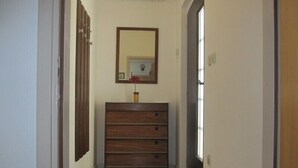 A hallway with a wooden dresser, a mirror, and a door. - House Marija (Pula)