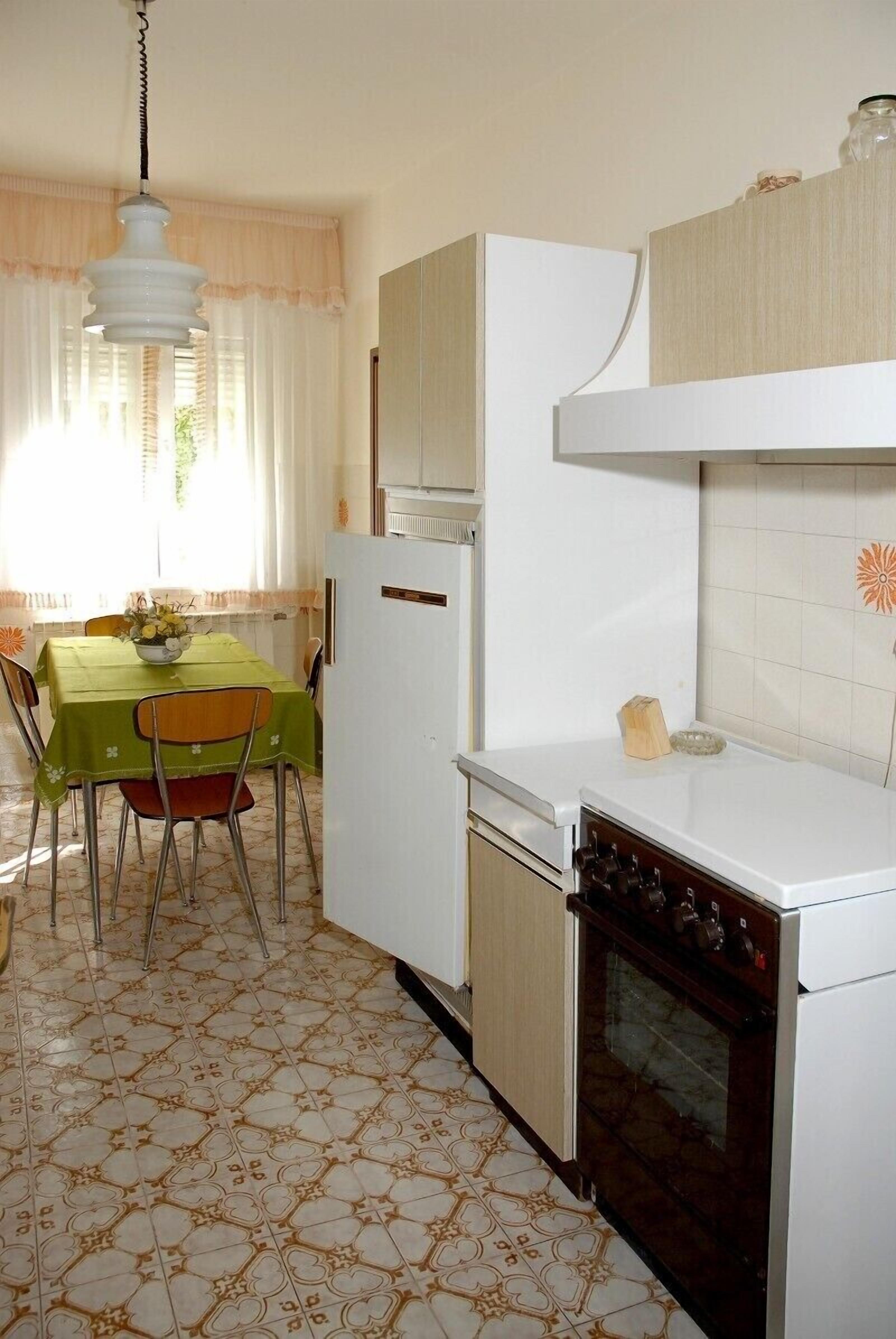 A compact kitchen with a dining area, featuring a refrigerator, oven, and a table with chairs.