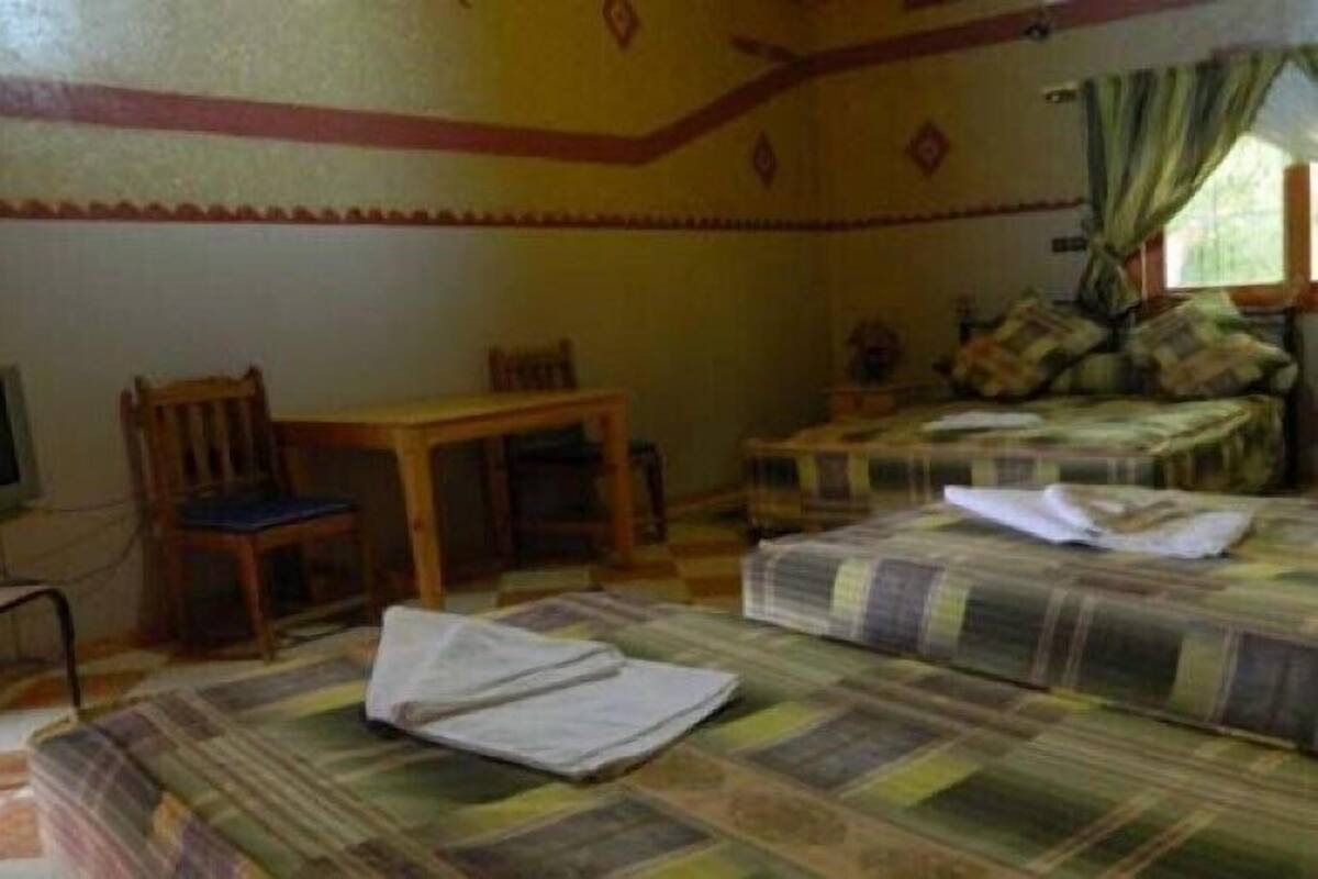 Een kamer met een bed, een stoel, een klein tafeltje en een televisie.