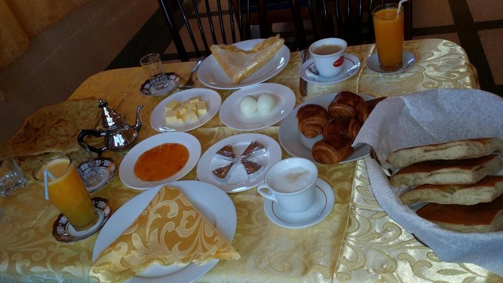 A breakfast table with various food items, including pastries, bread, and beverages.
