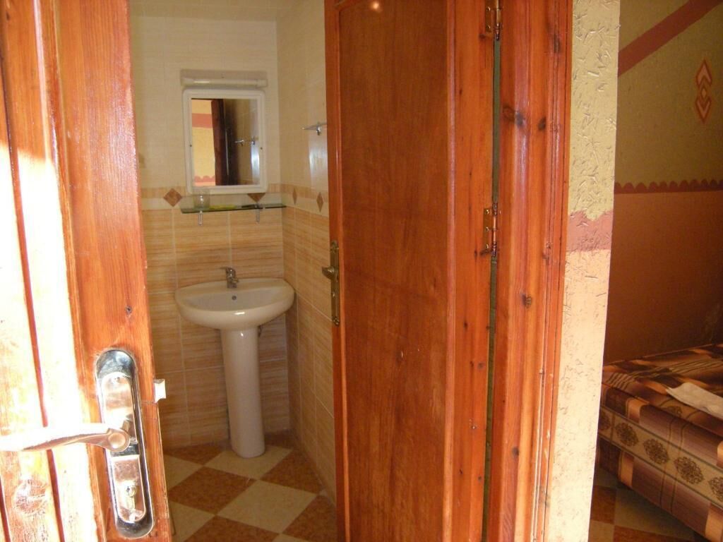 A bathroom with a wooden door, a sink, and a mirror.