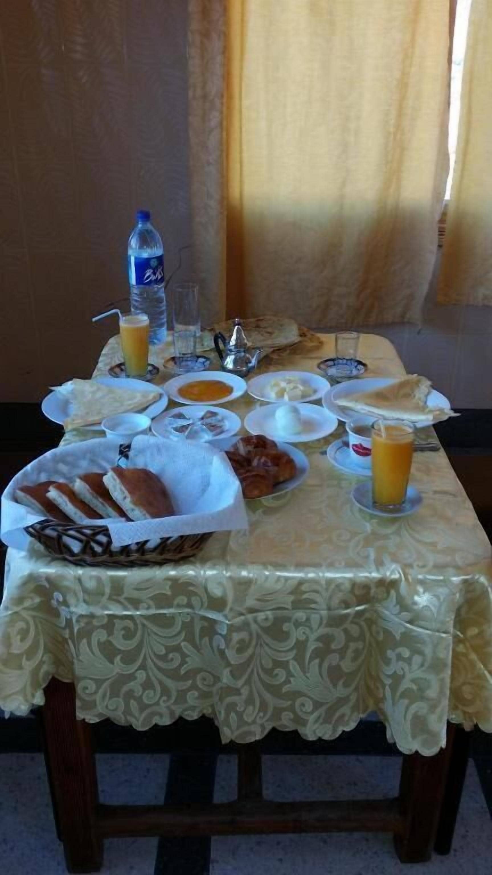 A table set with breakfast items including bread, eggs, and orange juice.