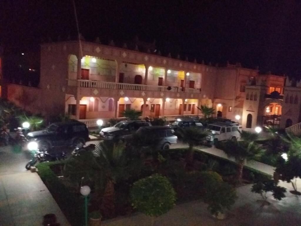 Een hotel met meerdere verdiepingen, een parkeerplaats en een goed verlichte gevel.