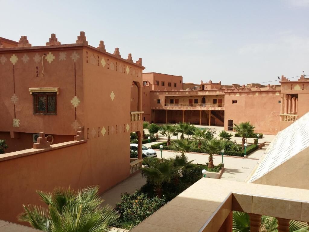 Ein Innenhof mit traditioneller Architektur, Palmen und blauem Himmel.