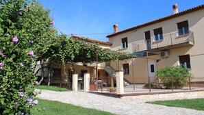 A building with a stone-paved courtyard, a covered outdoor seating area, and a balcony. - Villa Nino (Liznjan)