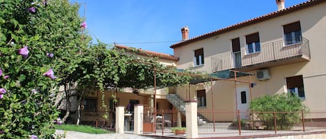 Un bâtiment doté d’une cour pavée de pierres, d’un espace extérieur couvert aménagé en coin salon et d’un balcon.