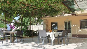 An outdoor patio with a table and chairs, surrounded by greenery and a pergola. - Villa Nino (Liznjan)