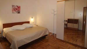 A bedroom with a bed, a bedside table, a mirror, and a coat rack. - Villa Nino (Liznjan)