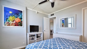 A bedroom with a bed, a TV on a stand, a ceiling fan, and a painting of a coral reef. - Dolphin Cove  PH 9 '90 day min stay with 2 week lead time' (Clearwater Beach)