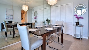 A modern dining area with a wooden table, clear chairs, and a chandelier. - Dolphin Cove  PH 9 '90 day min stay with 2 week lead time' (Clearwater Beach)