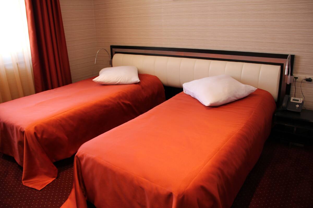 Two single beds with red bedding in a hotel room.