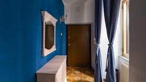 Een hal met een blauwe wand, een houten deur, een witte console tafel en vloertegels met een patroon.