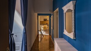 Een hal met patroontegels, een witte console tafel en een blauwe wand met een spiegel.
