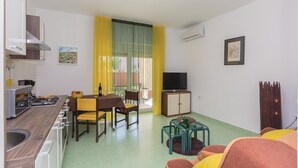 A compact living space with a kitchenette, dining area, and seating area. - Apartman Snježana (Pula)