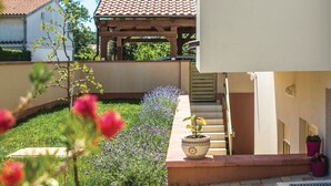 A courtyard with a pergola, a potted plant, and a staircase leading to a building. - Apartman Snježana (Pula)