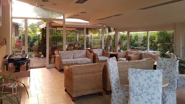 Un vaste espace intérieur aménagé avec des meubles en osier, de grandes fenêtres et une table de baby-foot.
