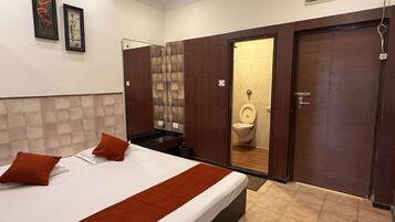 Una habitación de hotel con cama, baño con inodoro y espejo, y un armario.