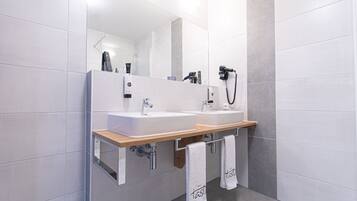Un baño moderno con dos lavamanos, un espejo grande y un secador de pelo en la pared.