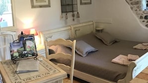 Ein gemütliches Schlafzimmer mit schrägen Wänden, einem Bett, einem Tisch mit Stuhl und einer Chandelier.