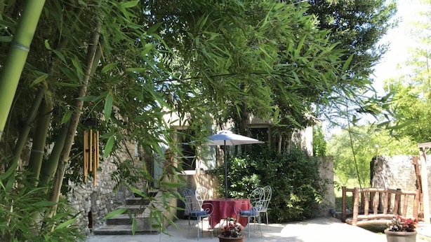 Eine Außenpatio mit Tisch und Stühlen, umgeben von Bambuspflanzen und einer Steinmauer.