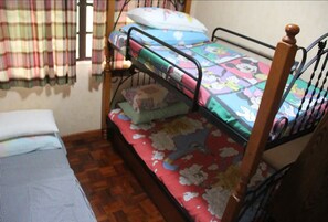 A bunk bed with a colorful bedspread, a wooden headboard, and a window with curtains. - Miguel's Place at Canyon Woods Resort (Laurel)
