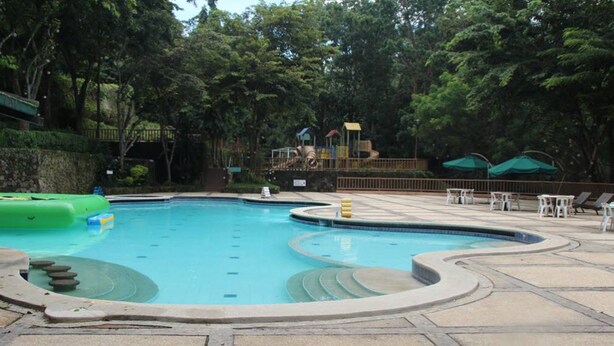 A swimming pool with a circular design, surrounded by a stone deck and trees. - Miguel's Place at Canyon Woods Resort (Laurel)