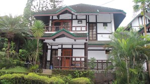 A two-story house with a balcony, surrounded by lush greenery. - Miguel's Place at Canyon Woods Resort (Laurel)