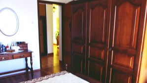 A bedroom with a large wooden wardrobe, a bedside table with toiletries, and a mirror on the wall. - Apartment Grgorinic (Pula)