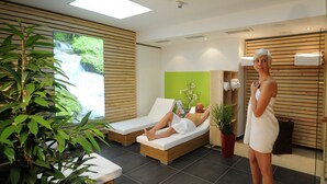 A spa room with two lounge chairs, a green wall, and a wooden panel wall. - Hotel Gasthof Posthalter (Zwiesel)