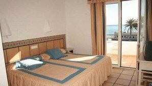 Ein Hotelzimmer mit Bett, Schreibtisch und Blick auf den Strand.