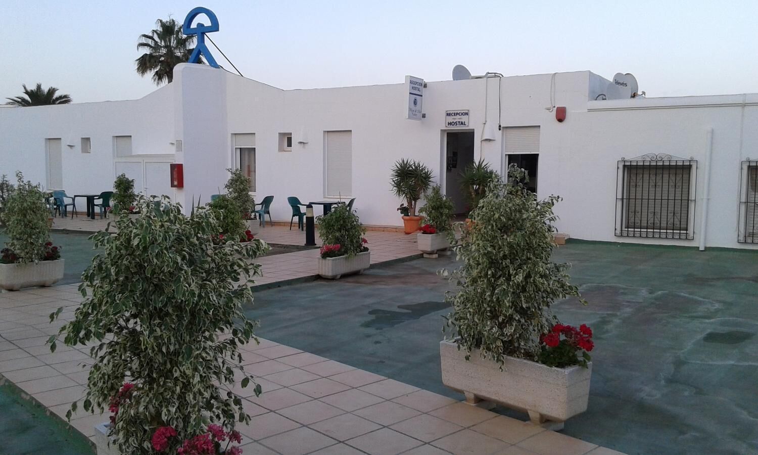 A hotel with a reception area, outdoor seating, and potted plants.
