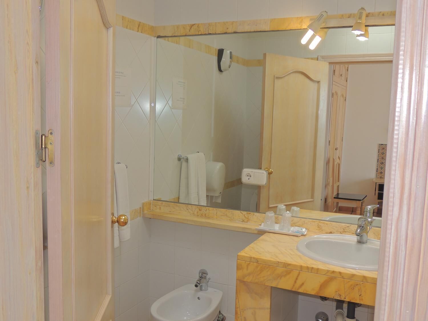 Un baño con tocador de mármol, lavabo, espejo y bidé.