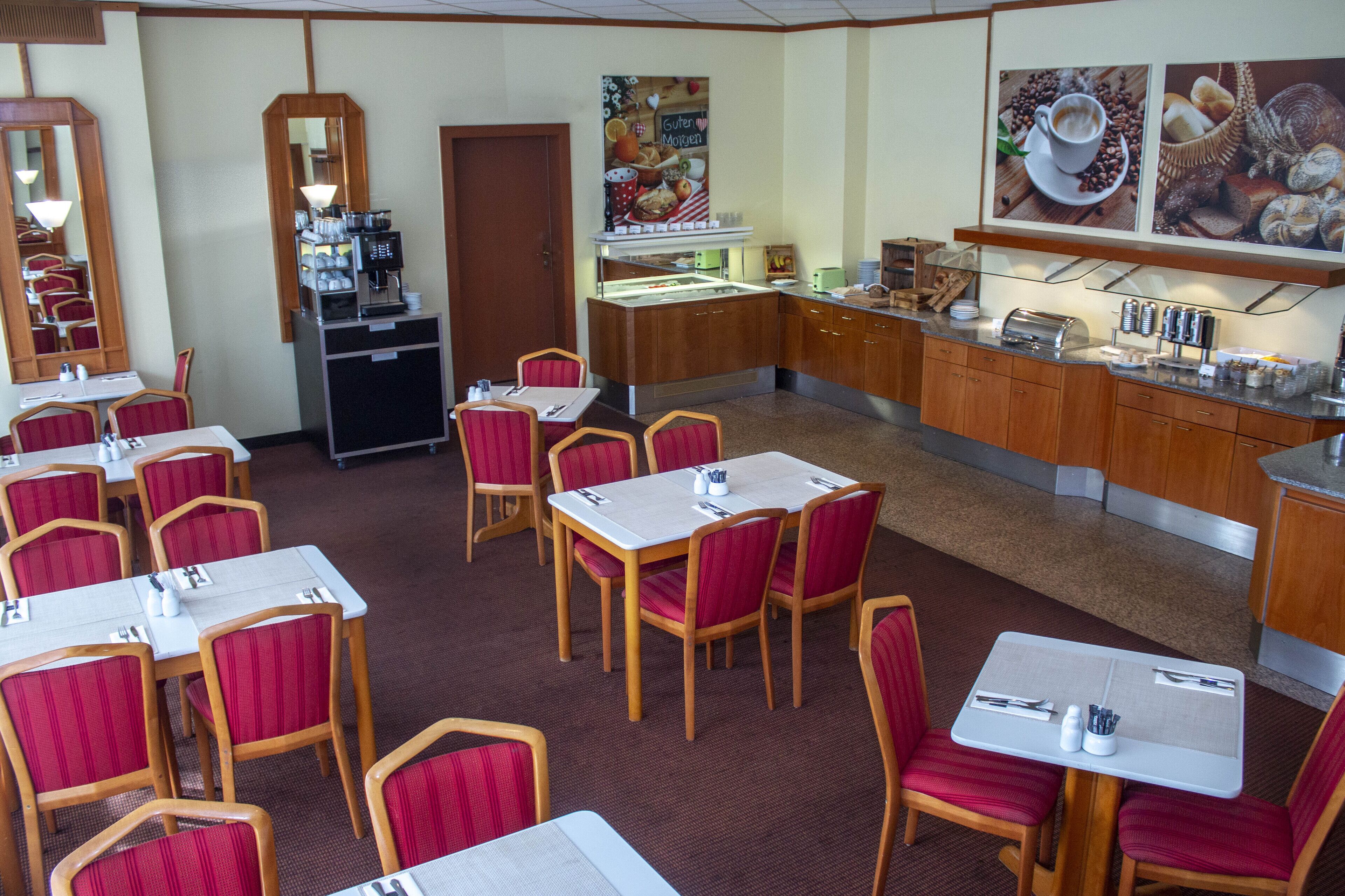 Un comedor de hotel con varias mesas y sillas, una estación de café y un mostrador de buffet.