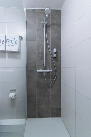 Standaard tweepersoonskamer | Badkamer | Een douche, een haardroger, handdoeken, zeep