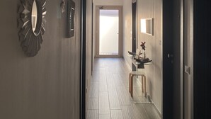 A hallway with a modern design, featuring a mirror, a wall-mounted sculpture, and a door leading to a bright room. - Hotel Villa Mare (Posada)