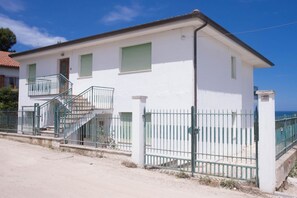 A two-story building with a balcony, a staircase, and a gated entrance.