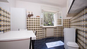 Una cucina compatta con una finestra, mobili bianchi e piastrelle decorative.
