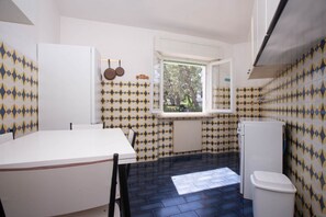 A compact kitchen with a window, white cabinets, and patterned tiles.