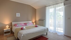 Een slaapkamer met een bed, nachtkastjes, een radiator en een raam met gordijnen.